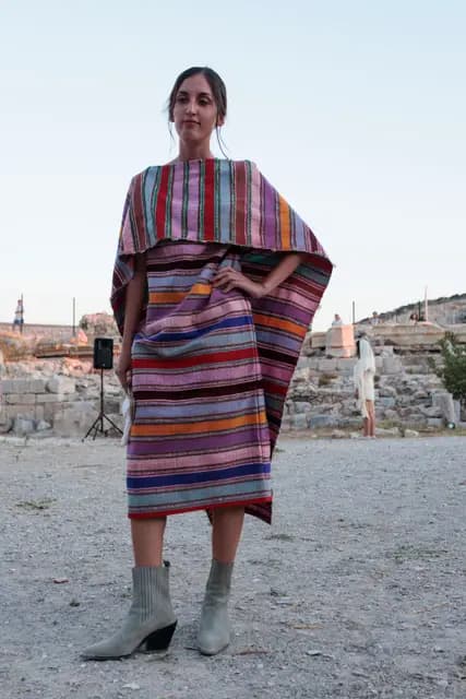 Wrapped in a colourful handwoven cape, a model looks into the camera in the sunset light.