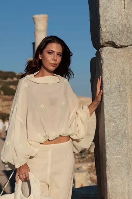 Hair in the wind, leaning against a column with a confident gaze — a close portrait in golden light.