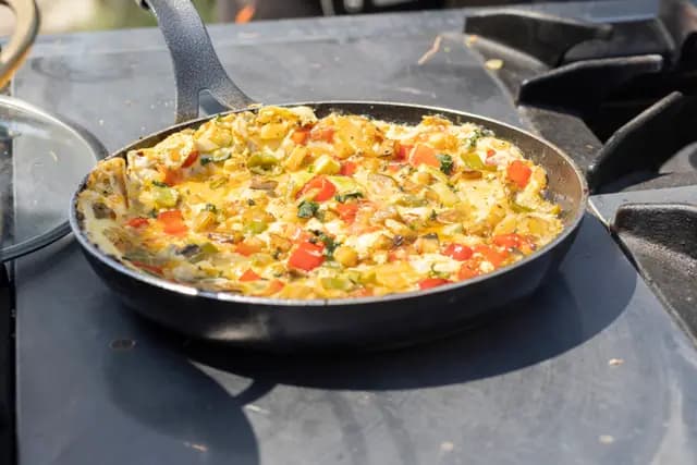 Eggs with vegetables cooking on the stove — the festival's local gastronomy served straight from the pan.