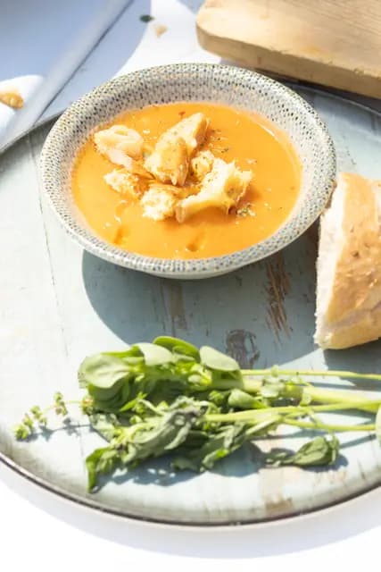 Tomato soup, torn bread and a bunch of purslane and basil — a spare overhead food frame.