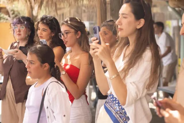A group of young visitors hold up their phones to record the workshop.
