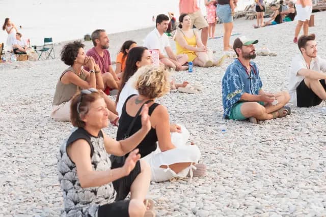 Cross-legged on the pebble beach, the audience follows the recital with applause.