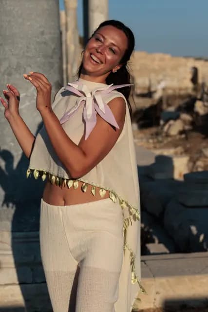 A model throws up her hands laughing in front of a column — the most candid moment of the show.