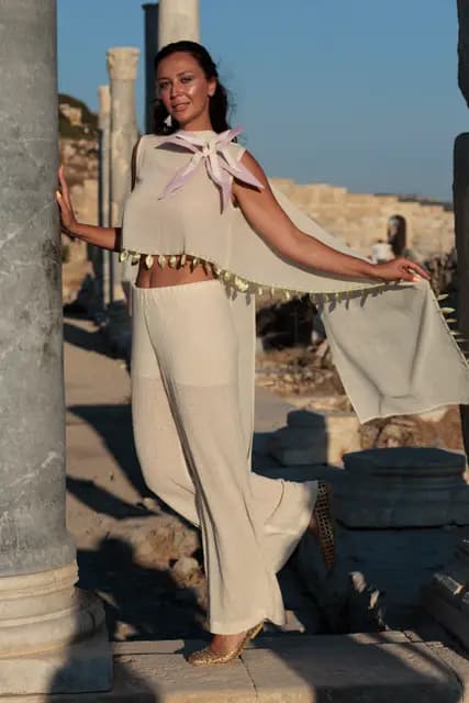 Holding on to a column, a model opens the tasselled fabric to one side to show its drape.