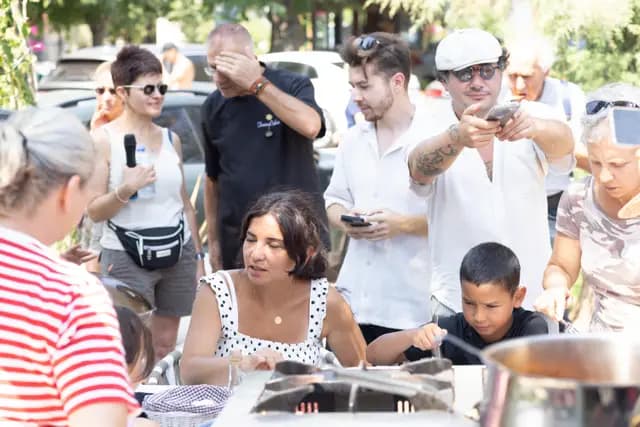 The crowd around the cooking show films it on their phones, children in the front row.