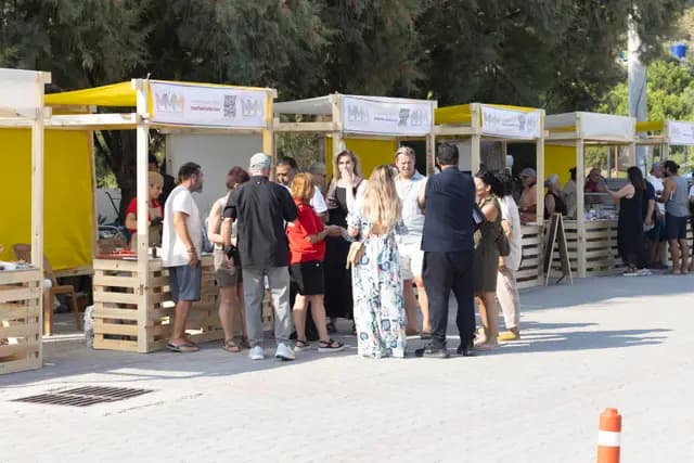 The row of yellow festival stands at Palamutbükü with visitors moving between them.