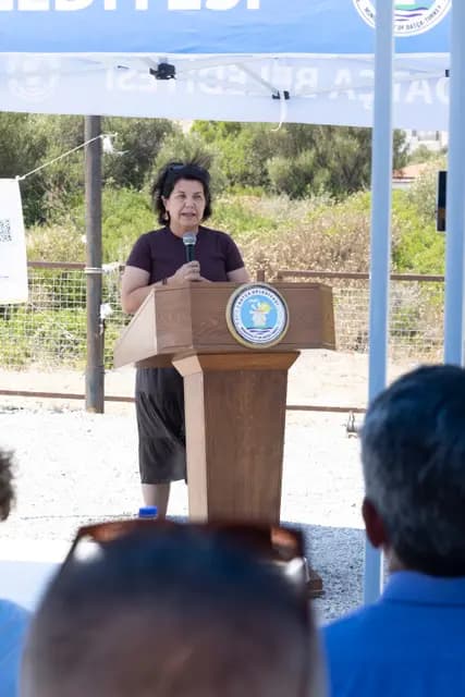 A speaker at the lectern turns to the audience and speaks with a smile.