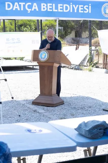 A speaker in glasses reads from his notes at the lectern.
