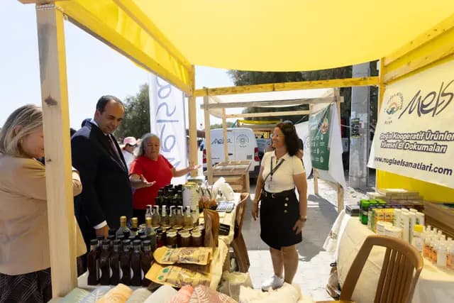 During the stand tour a producer explains her goods, local products lined up on the counter.