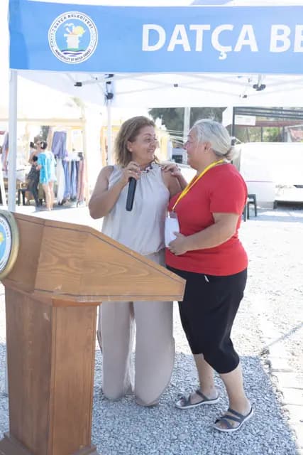 Two women share the microphone and speak together at the lectern.