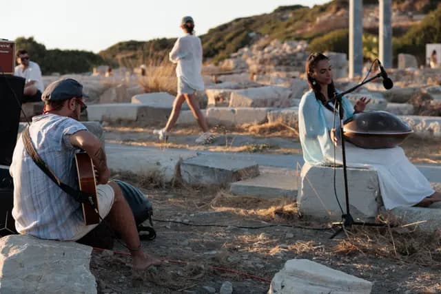 Guitar and handpan play together in the ancient site as visitors pass behind.